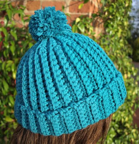 a close up of a person wearing a knitted hat with a pom - pom