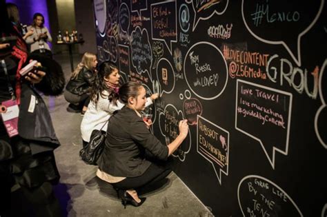 a woman writing on a blackboard with lots of chalk and stickers all over it