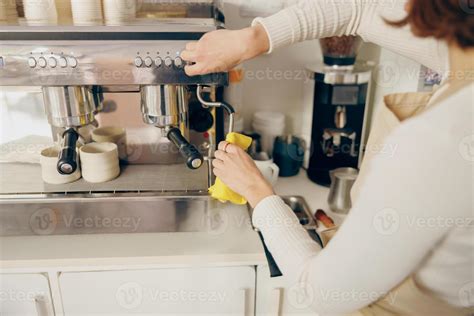 Close up of female barista cleaning coffee machine at coffee shop after ...