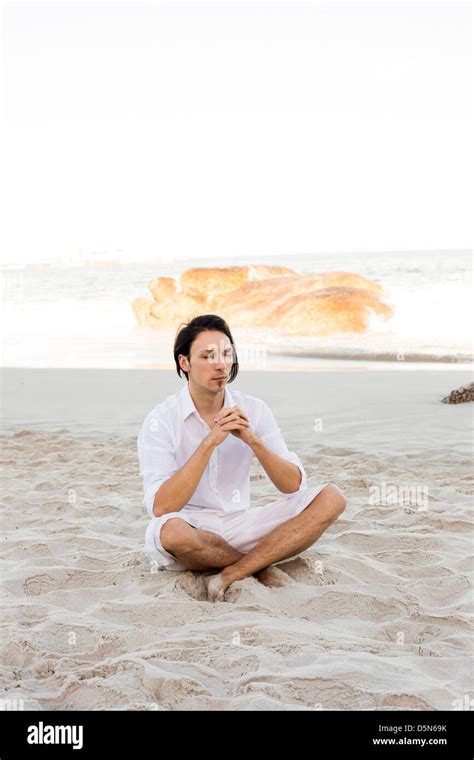 Young Man Meditating on Beach Stock Photo - Alamy