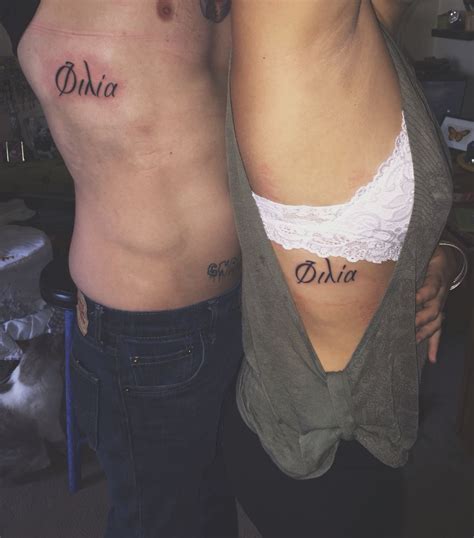 two people with tattoos on their stomachs and one has the word oka written on it