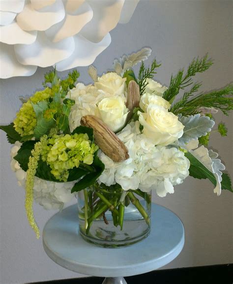 Fresh white and green floral arrangement made using Hydrangeas, roses, Amaranthus, driftwood ...