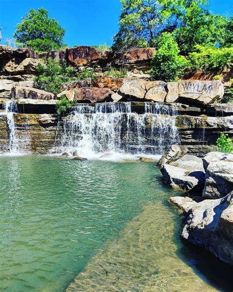 the waterfall is surrounded by large rocks and green water