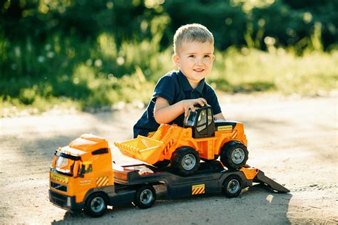 Boy in Blue T-shirt Riding Orange and Black Toy Car · Free Stock Photo