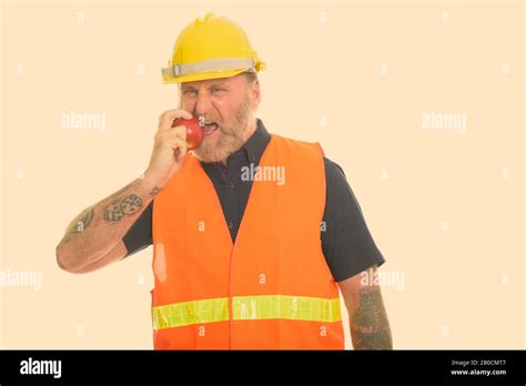 Mature bearded man construction worker with hand tattoos eating red apple Stock Photo - Alamy