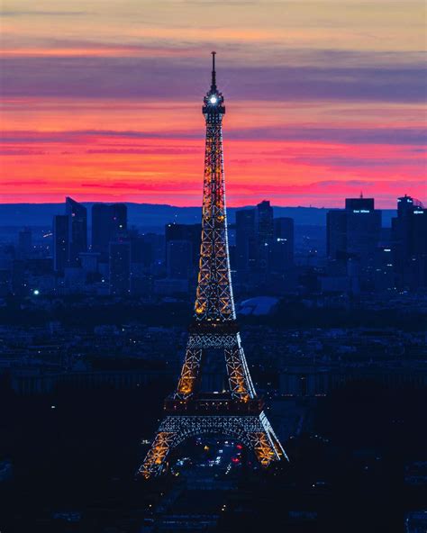 the eiffel tower lit up at night in paris, france with pink and blue sky