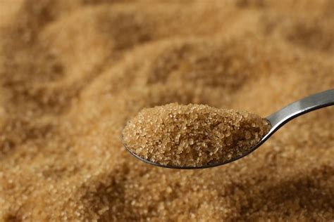 Premium Photo | Brown cane sugar crystals in a spoon over sugar background