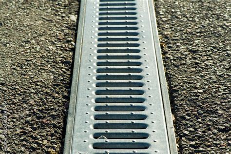 Gutter cover or sewer drain on roadside. street rain gutter Stock Photo | Adobe Stock