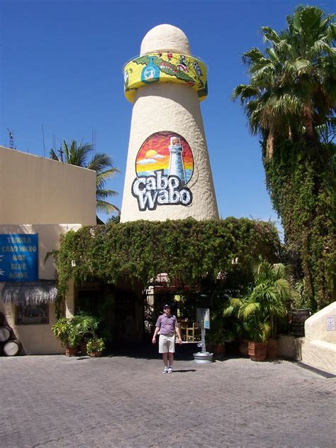 the entrance to cabo wabo with a woman standing in front and palm trees ...