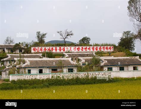 North Korean propaganda billboard in front of houses in a village ...