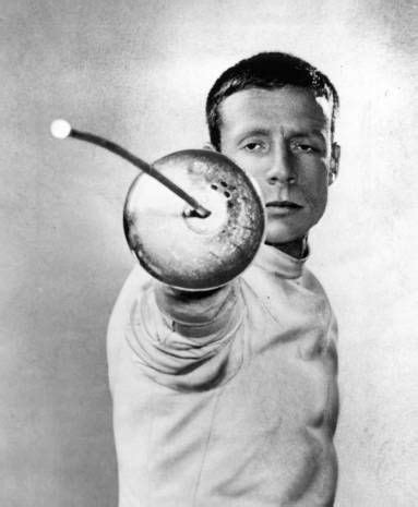 [ID: an epee fencer with his mask off, aiming his epee at the camera.] John DuPont in 1961 ...