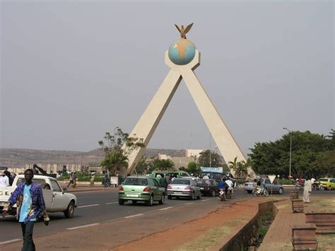 people are walking on the sidewalk in front of a large monument with a bird on it