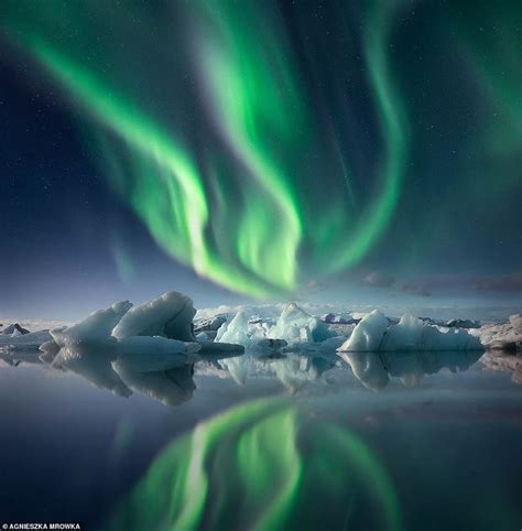 an aurora bore is reflected in the water with icebergs and snow floes