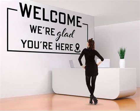 a woman standing in front of a welcome sign with the words we're glad ...