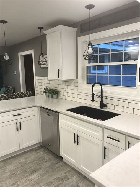 White shaker cabinets with solid surface countertops and flat black ...