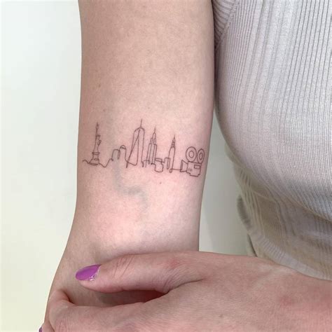 Fine line New York City skyline tattoo on the bicep.