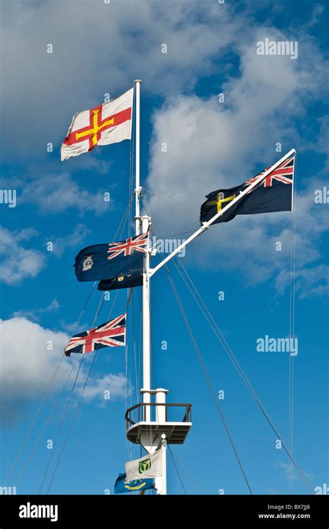 dh ST PETERS PORT GUERNSEY Guernsey flag on flag pole mast flagpole flags channel islands Stock ...