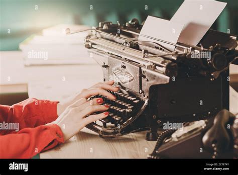 Secretary at old typewriter with telephone. Young woman using ...