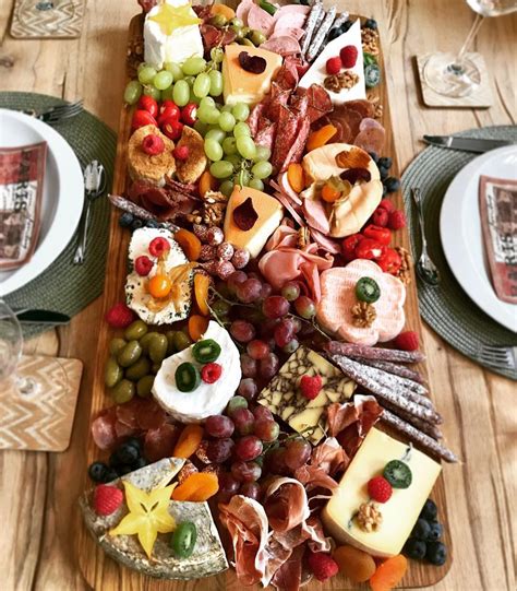 a wooden table topped with lots of different types of cheese and meats ...