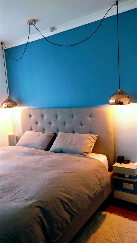 a bed with two lamps on either side of it and a blue wall in the background