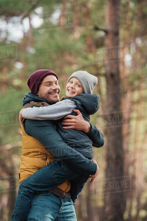 Happy father and son hugging in autumn forest - Stock Photo - Dissolve