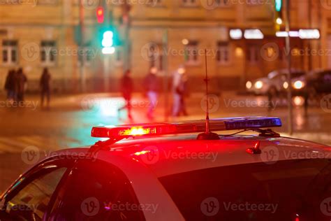 night police car lights in city street with blurry pedestrians crossing ...