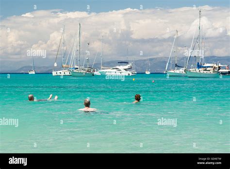 holidaymakers relaxing in the clear turquoise sea at Lakka, Paxos - looking out towards luxury ...