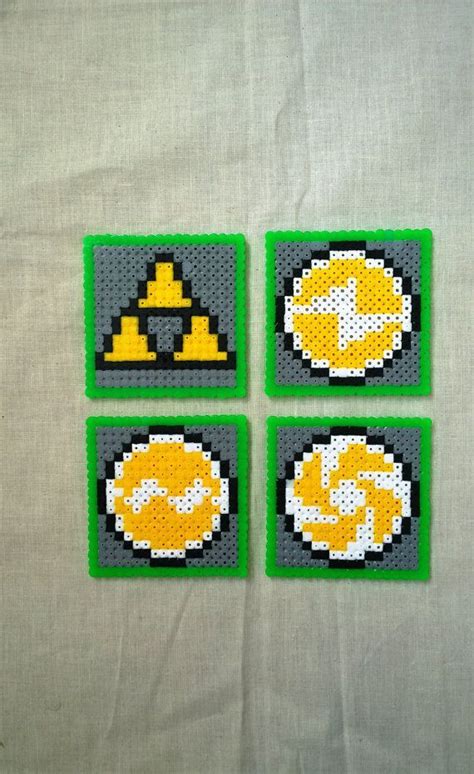 four coasters made out of perler beads on a white tablecloth with green edges