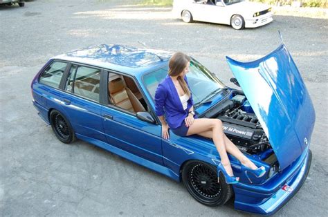 a woman sitting on the hood of a blue car with an open hood in front of her