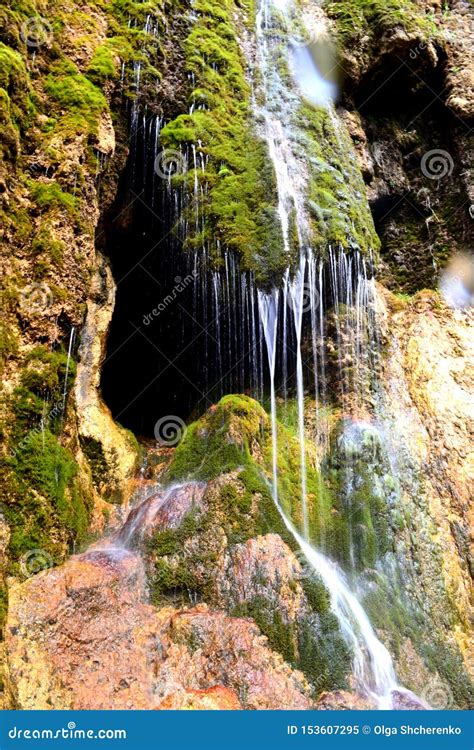 Cave Entrance Hidden Behind a Small Waterfall. Stalactite Cave in the Mountains of the North ...