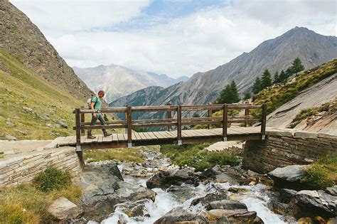 "A Man Crossing A Bridge Over A River In The Mountains." by Stocksy ...