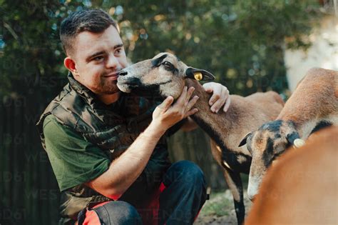 Caretaker with down syndrome taking care of animals in zoo, stroking a ...