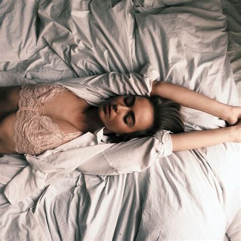 a woman laying in bed with white sheets