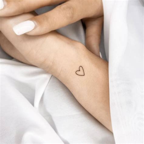 Minimalist heart tattoo on the wrist.