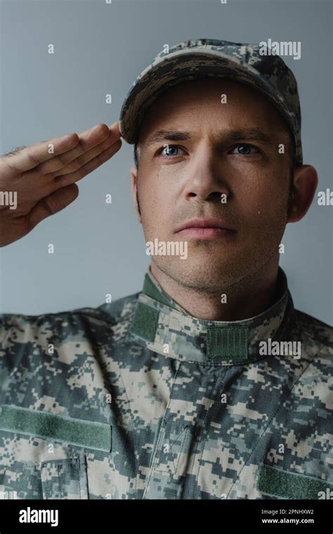 sad soldier in military uniform crying and saluting during memorial day isolated on grey Stock ...