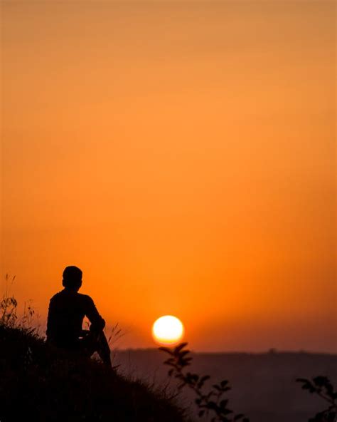 Silhouette of Sitting Person at Sunset · Free Stock Photo