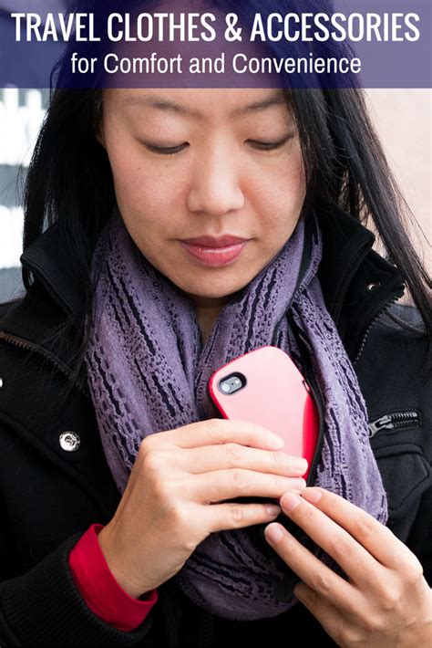 a woman looking at her cell phone while wearing a scarf and jacket with ...