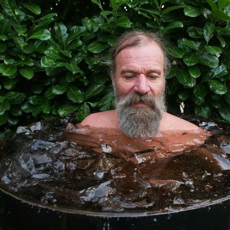 a man with a beard is sitting in a tub filled with water and ice cubes