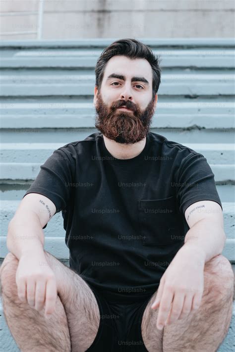 Un homme avec une barbe assis sur une chaise photo – Élongation Photo ...