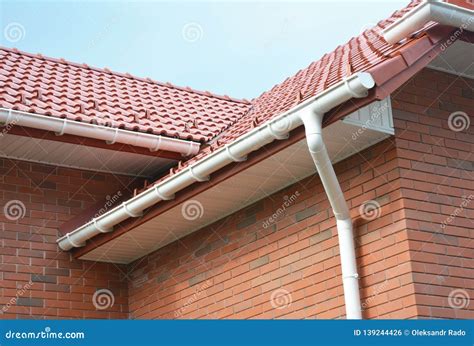 Rain Gutter Pipe System. Close Up on Brick House with Roof Tiles and Plastic Roof Gutter Pipes ...