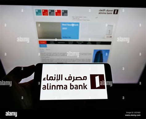 Person holding mobile phone with logo of Saudi Arabian financial company Alinma Bank on screen ...