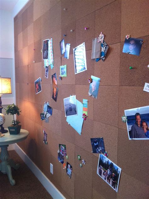 a cork board with pictures and photos pinned to it on the wall next to a table