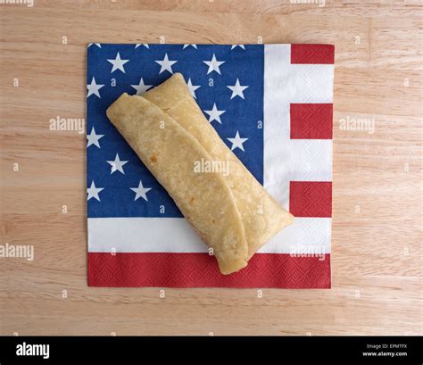 Top view of a microwaved chimichanga on an American flag motif napkin atop a wood table top ...