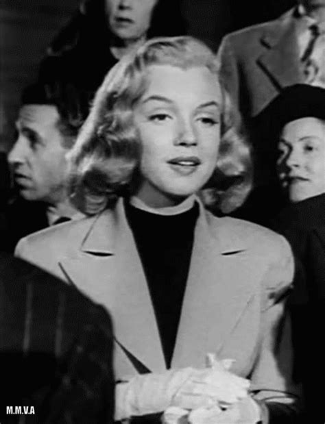 a black and white photo of a woman standing in front of other people wearing hats