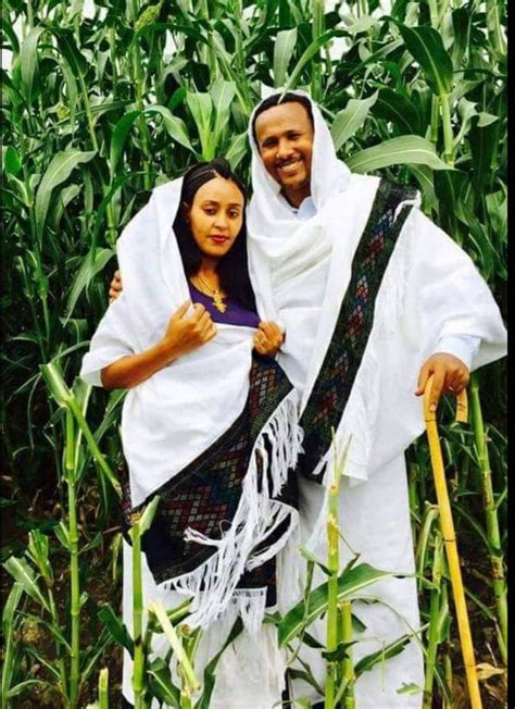 a man and woman standing in the middle of a corn field