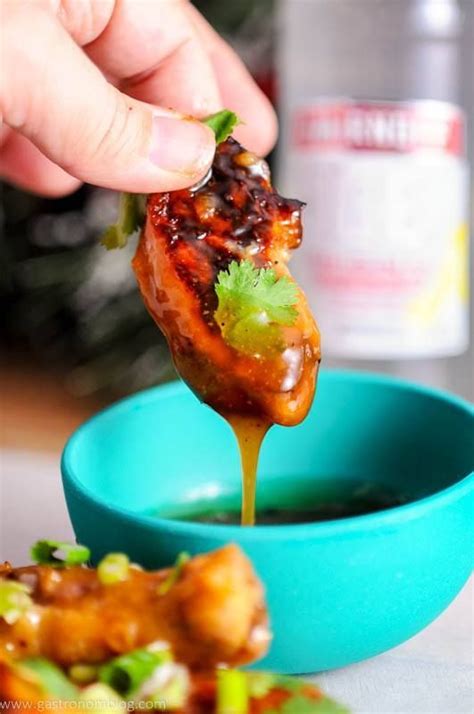 A citris Asian Chicken wing in a dipping sauce being held by a hand. | Asian chicken wings ...