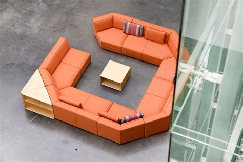 an orange couch sitting on top of a gray floor next to a glass wall filled with furniture