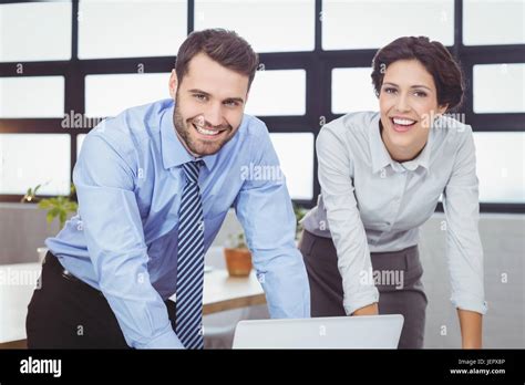 Happy business people by laptop at desk Stock Photo - Alamy