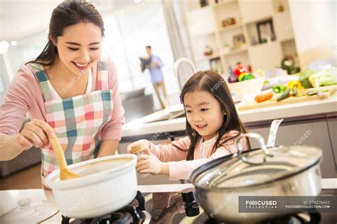 Happy asian mother and daughter cooking together in kitchen — casual ...