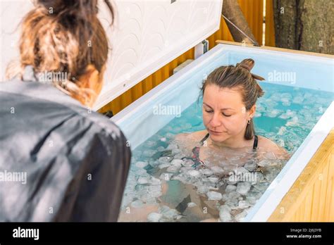 Girl or woman bathing in the cold water among ice cubes with instructor ...